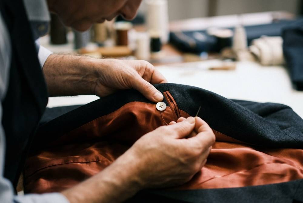 Gros plan sur les finitions d'un costume de mariage : doublure terracotta et boutons de nacre